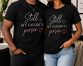 Couple wearing Still My Favorite Person unisex black T-shirts with natural straight hems